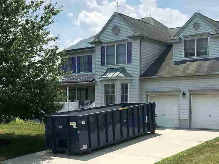Roll-off dumpster in the driveway of a home (Estate Clean Out Services) by Affordable Moving Solutions of Ohio