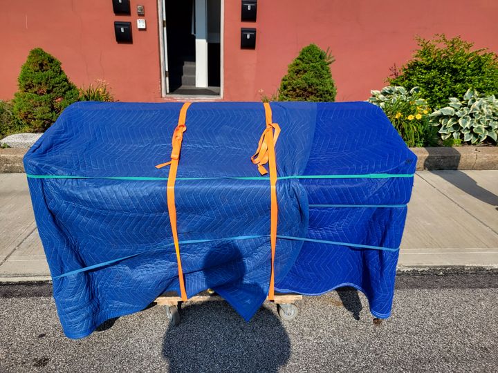 Piano wrapped in blue moving blankets outdoors (Piano Moving Services) by Affordable Moving Solutions of Ohio